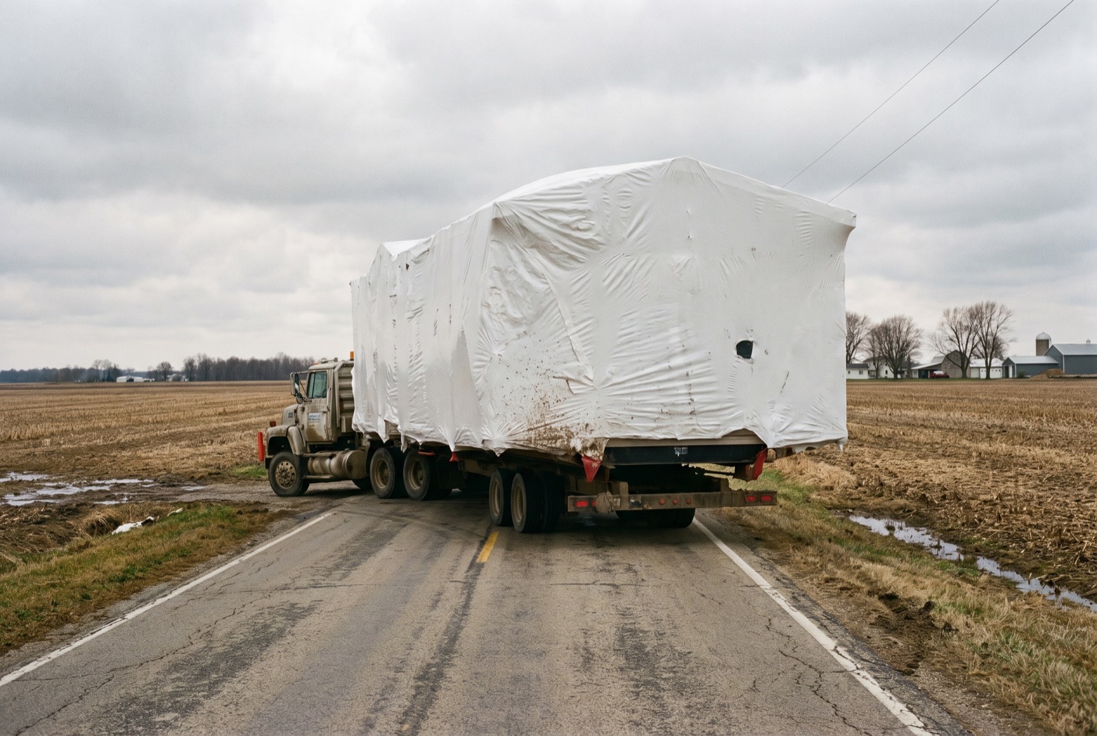 Half of a manufactured home on a transport trailer on a two-lane road